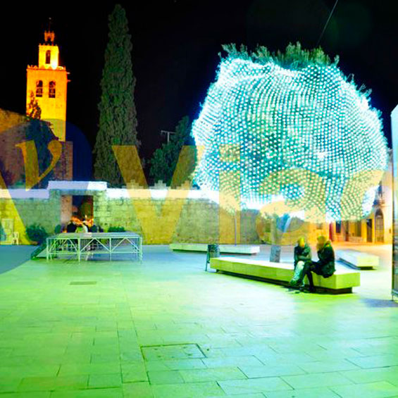 Árbol iluminado con red de luz en una plaza
